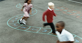children in schoolyard playing hopscotch